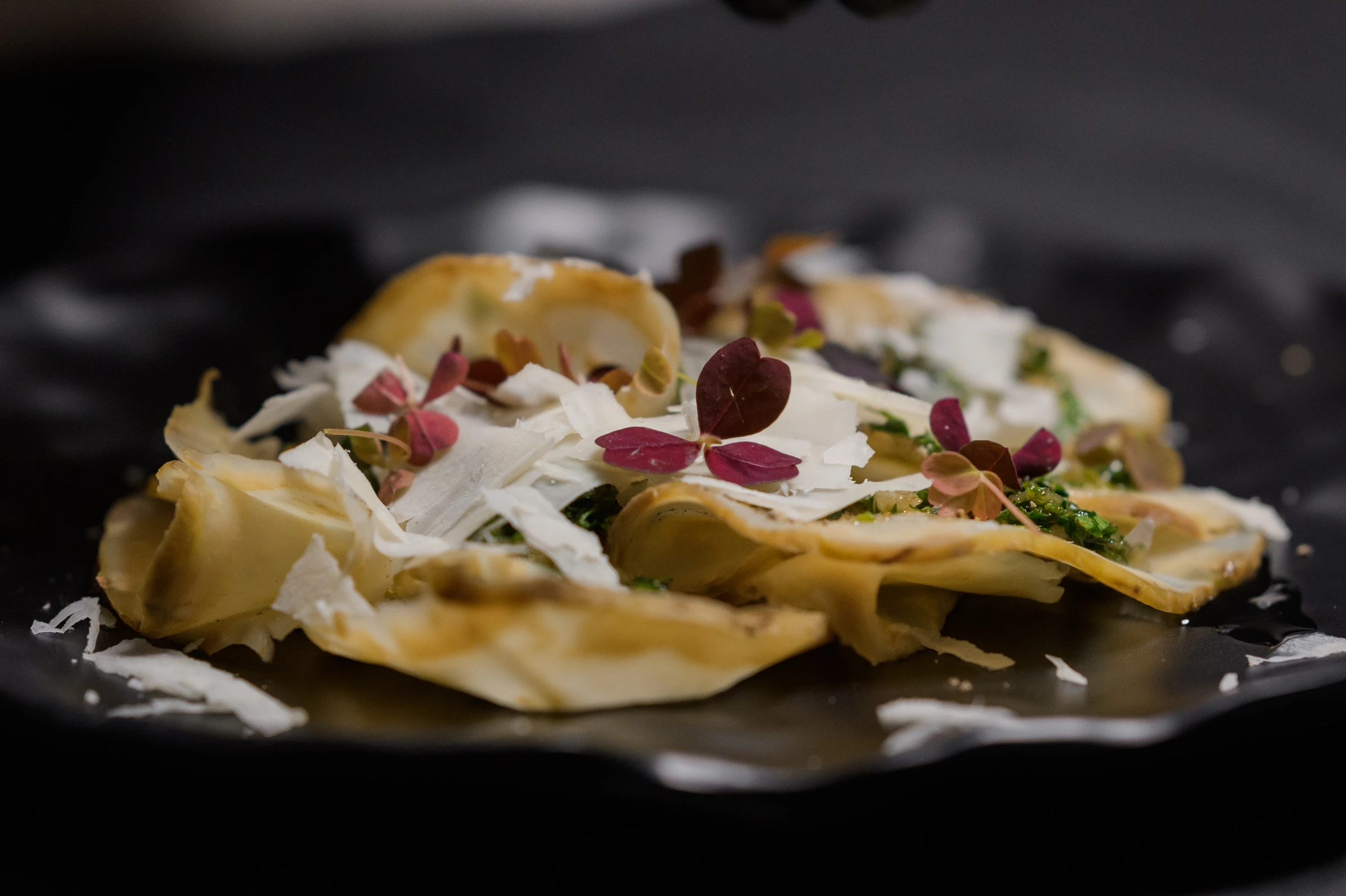 Хрустящая слоёная закуска с сыром и микрозеленью на чёрной тарелке